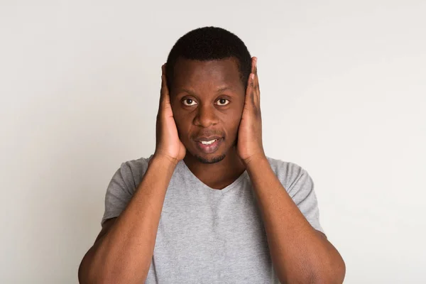 Porträtt av stilig svart man som täcker öronen isolerad på vit bakgrund — Stockfoto