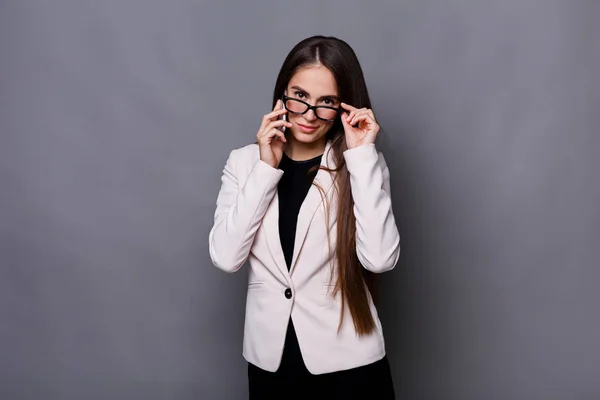 Щаслива молода кавказька бізнес-леді телефонує на мобільний телефон на сірому фоні — стокове фото