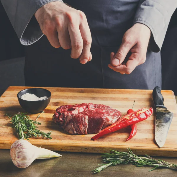 Chef tempero costela olho bife na tábua de madeira no restaurante kitch — Fotografia de Stock