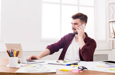 Cep telefonu üzerinde konuşurken neşeli genç işadamı