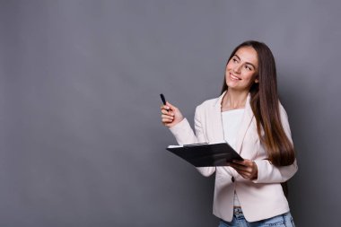 Gri arka plan üzerinde not defteri ile kendine güvenen kadın