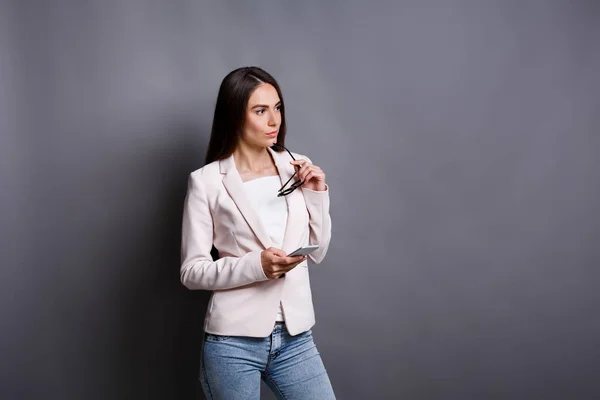 Mujer concentrada con smartphone sobre fondo gris — Foto de Stock