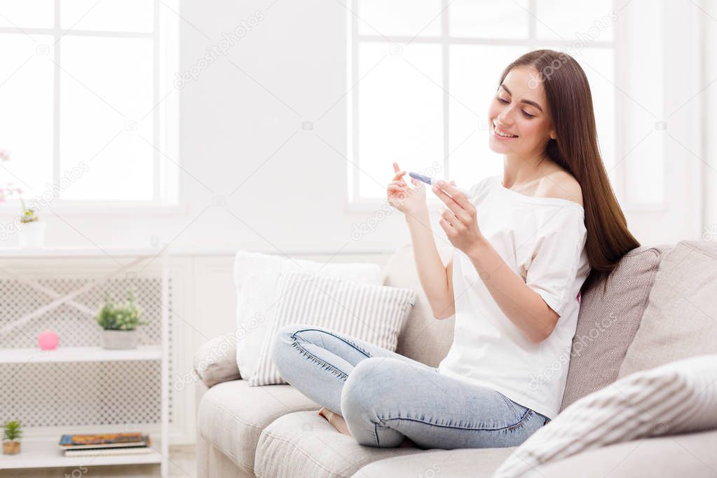 Happy girl with pregnancy test at home