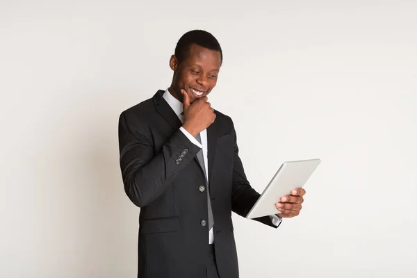 Hombre de negocios sonriente y poseedor de traje de pie, sosteniendo la tableta en las manos. Retrato — Foto de Stock