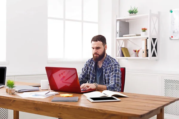 Σοβαρός επιχειρηματίας που εργάζεται με το laptop στο μοντέρνο λευκό γραφείο — Φωτογραφία Αρχείου