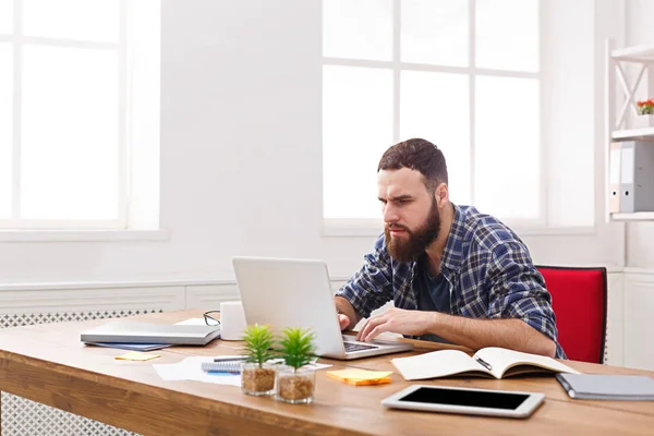 Joven hombre de negocios que trabaja con el ordenador portátil en la oficina blanca moderna — Foto de Stock