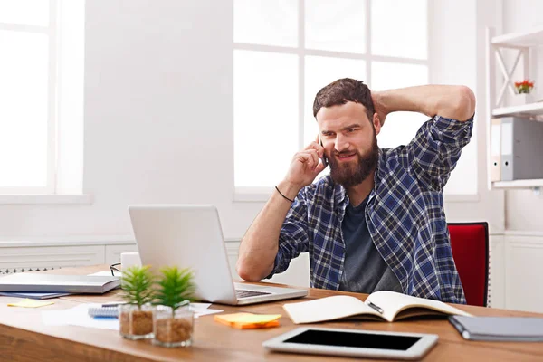 Genç memnun işadamı bir telefon konuşma modern beyaz ofiste vardır.