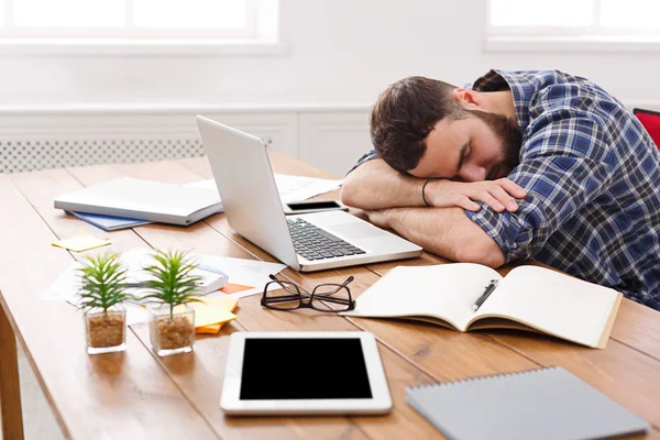 Sleeping overworking businessman with laptop in modern white office