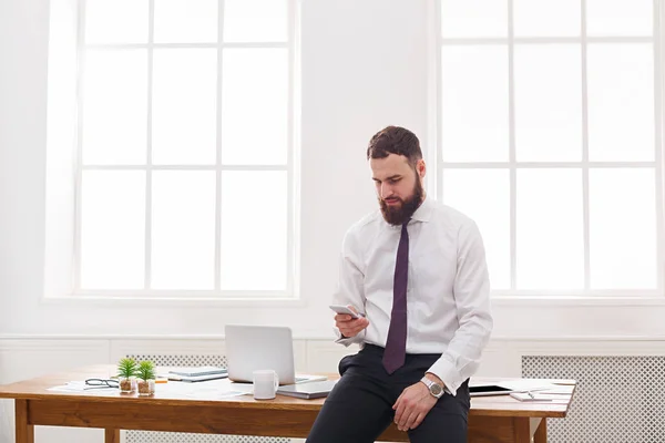 Empresário pensativo usando telefone celular no escritório moderno branco — Fotografia de Stock