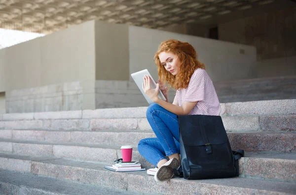 Genç Kızıl saçlı kız öğrenci tablet, merdivenlerde açık havada oturma ile çalışma