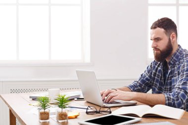 Modern beyaz ofis içinde laptop ile çalışan dalgın genç işadamı