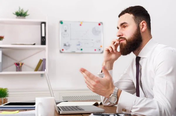 Seriöser Geschäftsmann telefoniert mit Laptop in modernem Büro — Stockfoto