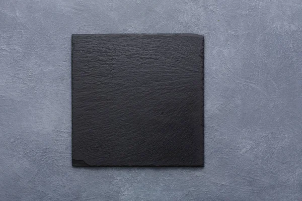Piastra di ardesia nera quadrata vuota su spazio copia backround grigio rustico — Foto Stock