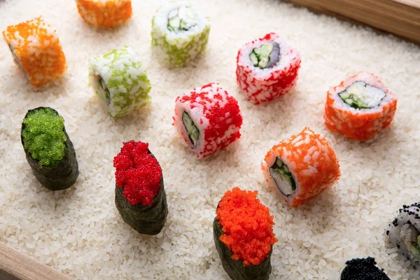 Rolos de sushi e gunkan sobre fundo de arroz branco e textura — Fotografia de Stock