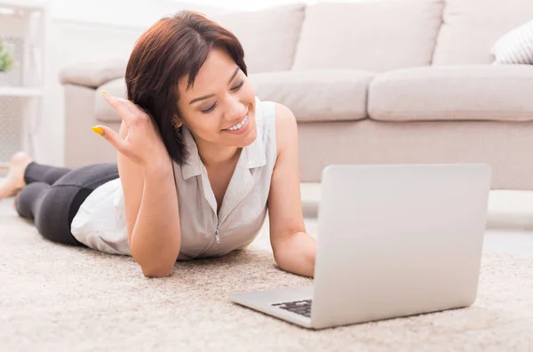 Mi godo il tempo libero a casa. Ragazza felice con il computer portatile sul pavimento — Foto Stock