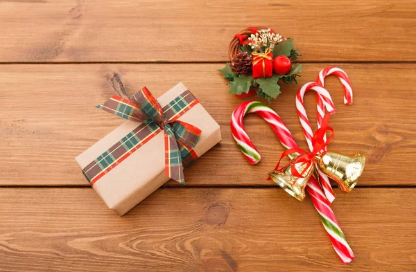 Corona de Navidad, caja de regalo en papel artesanal y dulces de Navidad sobre fondo rústico de madera — Foto de Stock