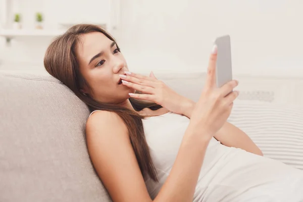 Joven chica sorprendida con teléfono inteligente en casa — Foto de Stock