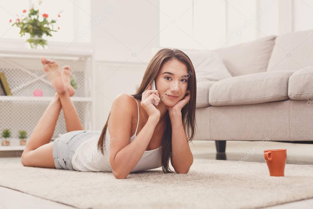 Young girl talking on mobile phone lying on floor