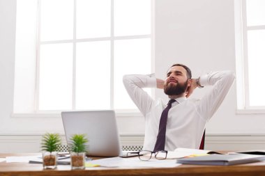 Modern beyaz ofis içinde laptop ile mutlu ve rahat iş adamı