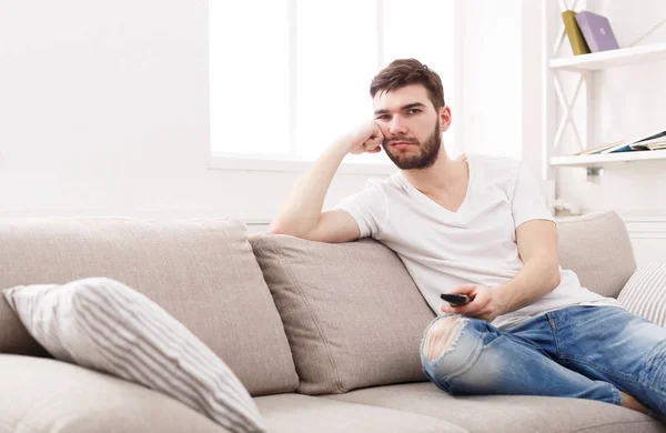 Jovem homem chato assistindo televisão em casa — Fotografia de Stock