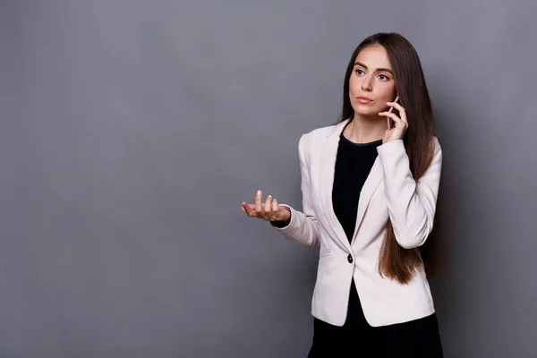 Jonge zakenvrouw heeft call. Studio opname op een grijze achtergrond — Stockfoto