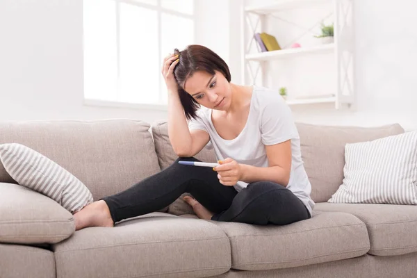 Orolig tjej med graviditetstest som sitter på soffan — Stockfoto