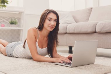 Yerde yatarken dizüstü kullanan genç kız