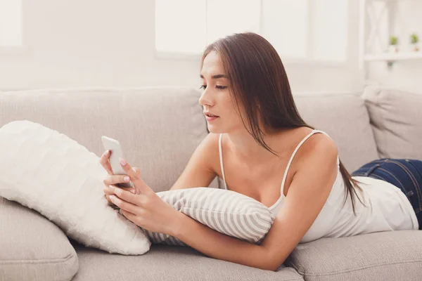Ung flicka med mobiltelefon på soffa — Stockfoto