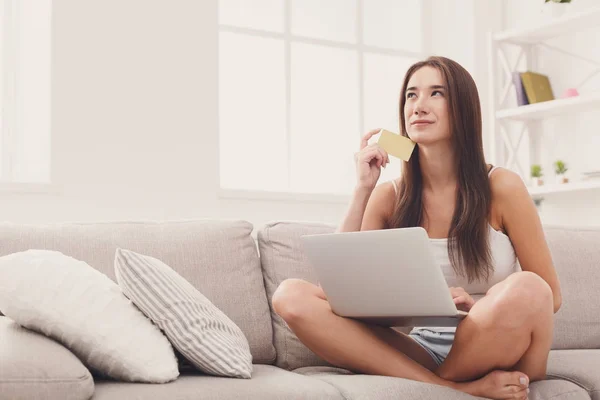 Pensive woman shopping online with credit card — Stock Photo, Image