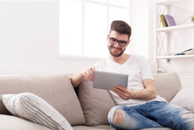 Genç adam evde tablet üzerinde okuma