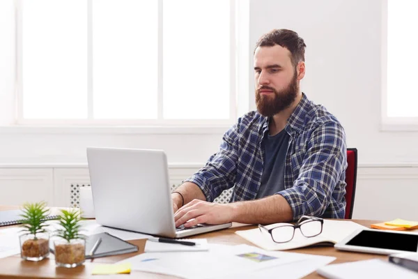 Ung koncentrerad affärsman med laptop i modern vit office — Stockfoto