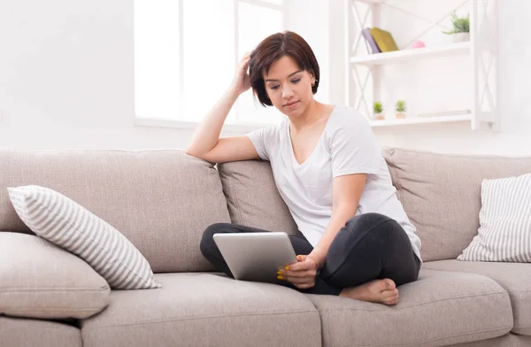 Pensive girl at home chatting online on tablet — Stock Photo, Image