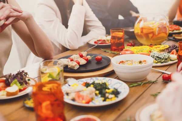 Mensen drinken lenonade en eten op tafel geserveerd diner — Stockfoto