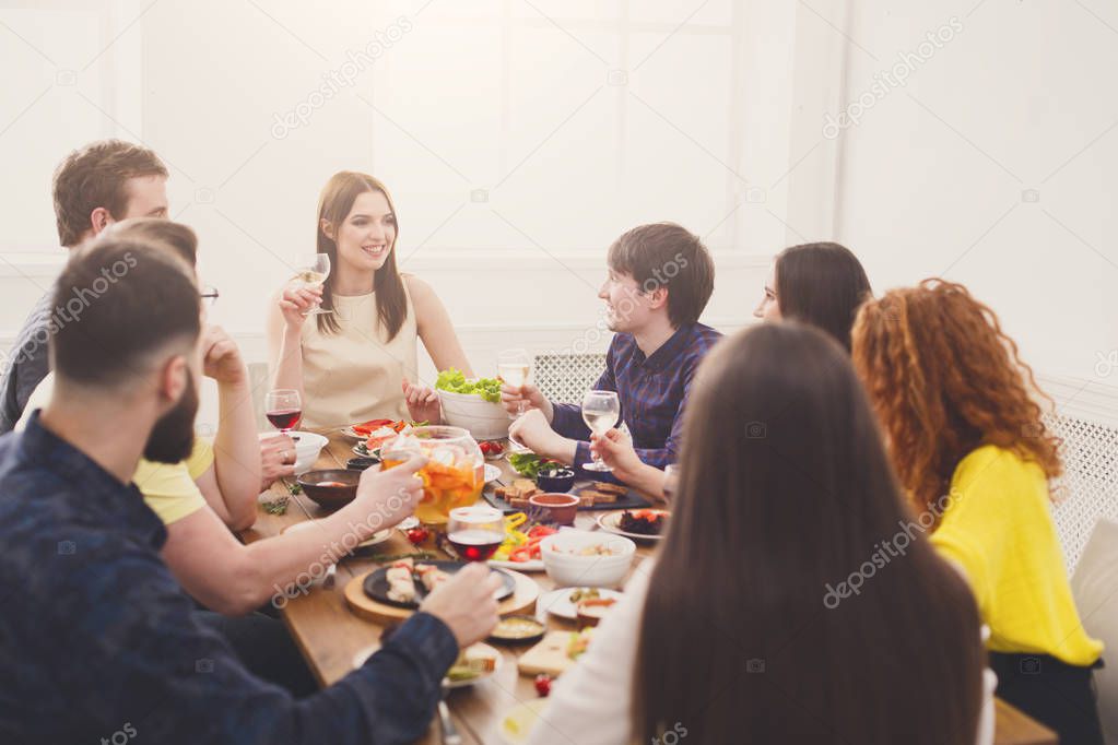 Group of happy young people talking at dinner table, friends party