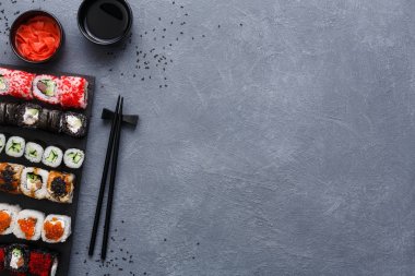 Üstten Görünüm suşi maki ve rulo rustik gri ve susam arka plan üzerinde kümesi