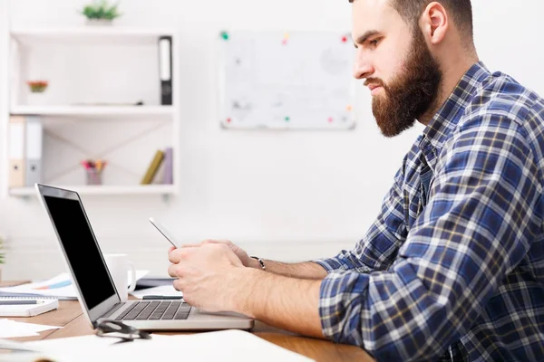 Ung affärsman i office med mobiltelefon av den bärbara datorn — Stockfoto