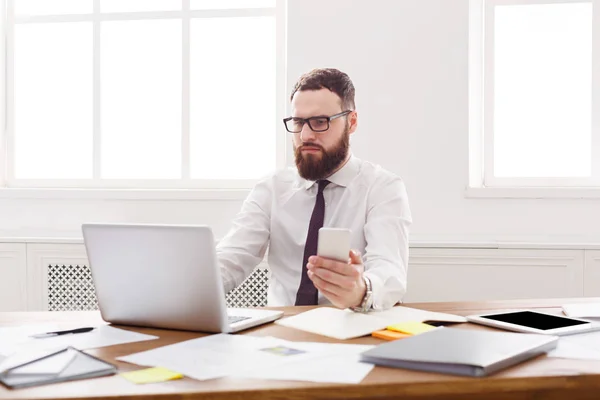 Fundersam affärsman med laptop i modern vit office — Stockfoto