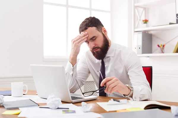 Стрессовый бизнесмен с ноутбуком в современном белом офисе — стоковое фото