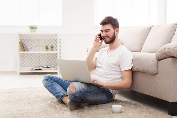 Sonriente joven en casa con portátil y móvil — Foto de Stock