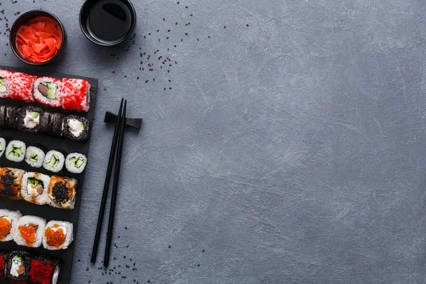 Widok z góry zestaw sushi maki i bułki na rustykalny szary i sezamu tło — Zdjęcie stockowe