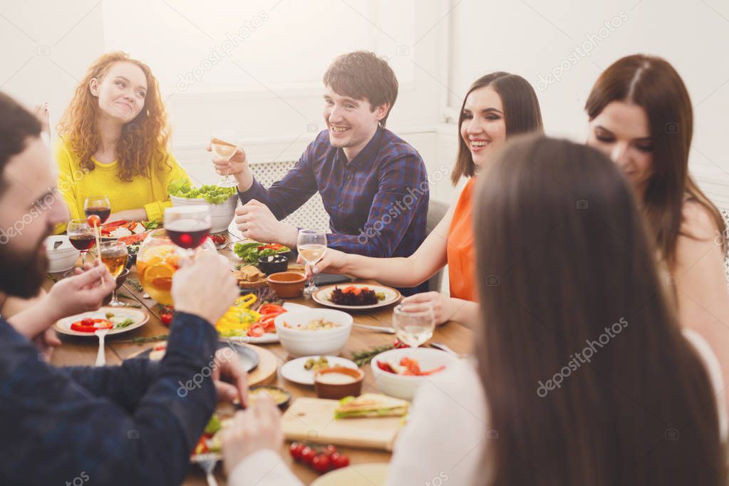 Group of happy young people at dinner table, friends party