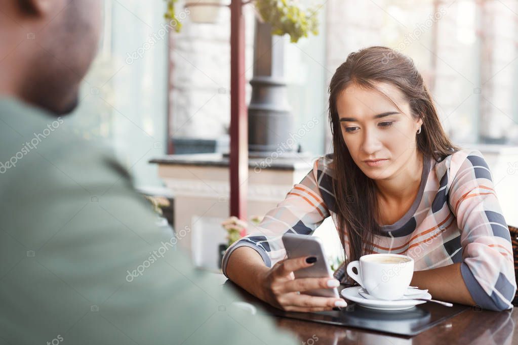Young bored girl drinking coffee on date at a cafe