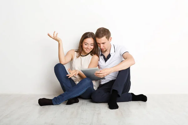 Couple choqué utilisant un ordinateur portable, assis sur le sol — Photo