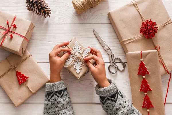 Womans hands wrapping christmas holiday present with craft twine