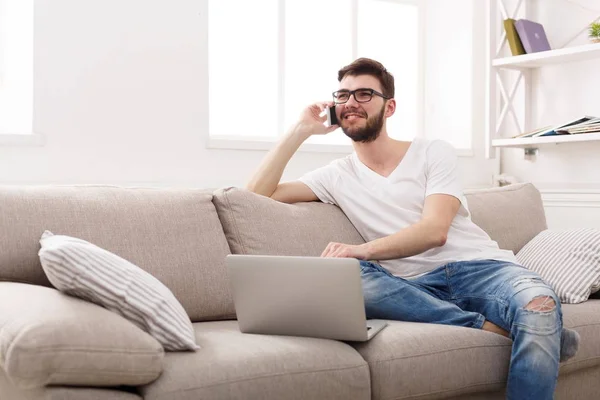 Sonriente joven en casa con portátil y móvil — Foto de Stock