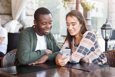 Genç çift hareket eden smartphones kafede kullanarak