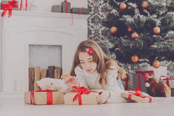 Bella ragazza in cappello di Babbo Natale scartando regali di Natale — Foto Stock