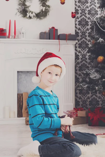 Bonito menino feliz em santa chapéu com presentes de Natal de brinquedo — Fotografia de Stock