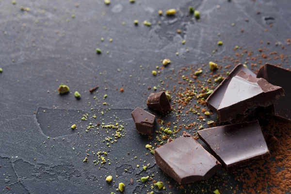 Разбитые кусочки шоколада и какао порошок на черном фоне — стоковое фото