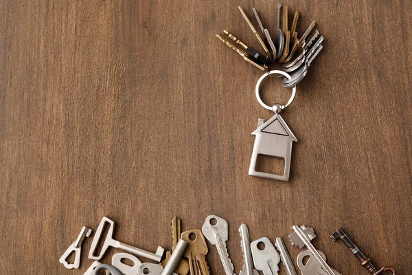 Связка ключей с домовой безделушкой на деревянном столе — стоковое фото